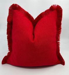 a red pillow with fringe edges on a white background