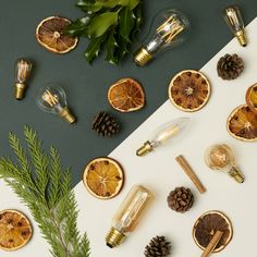 an assortment of orange slices, pine cones and other christmas decorations on a white table