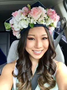 a woman sitting in a car wearing a flower crown on her head and smiling at the camera