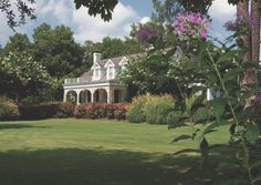 a white house surrounded by trees and flowers