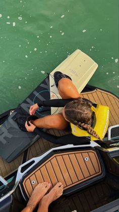 a woman sitting on the back of a boat with her feet up in the water