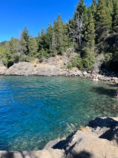 the clear blue water is surrounded by rocks and trees