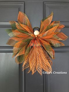 an orange and green wreath hanging on the front door