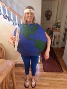 a woman in tights and headband holding up a giant blue earth pillow