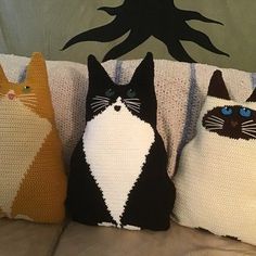 three pillows made to look like cats are sitting on a couch next to each other