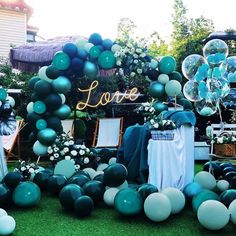 an outdoor party with balloons and streamers on the grass, blue and green decorations