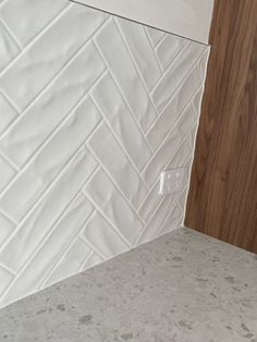 a kitchen counter with white tile and wood in the backround, next to a sink