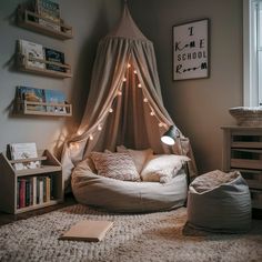 a bedroom with a canopy bed and some books on the floor next to a window