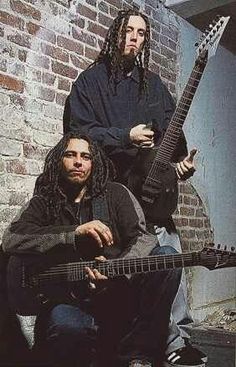 two men sitting next to each other holding guitars