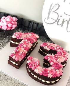 a chocolate cake with pink frosting and the number 50 spelled out in front of it