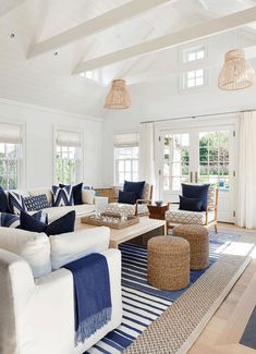 a living room filled with white furniture and blue pillows on top of it's couches