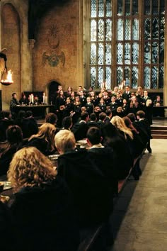 a large group of people sitting in front of a stage with candles on the table