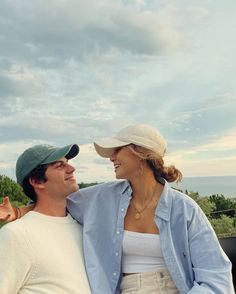 a man and woman standing next to each other on top of a roof with trees in the background