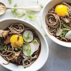 two white bowls filled with noodles, mushrooms and an egg on top of each other