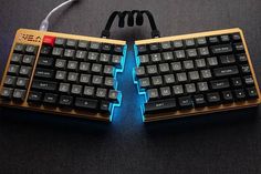 two keyboards with glowing blue keys are on a black surface, one is broken and the other has wires attached to it