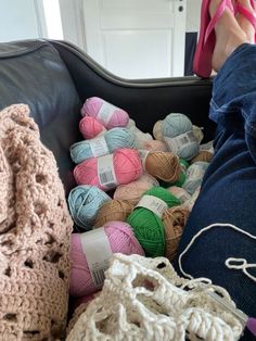 a person laying on a couch with crocheted balls of yarn