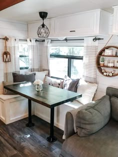 a living room with couches and a table in front of a window that has blinds on the windowsill