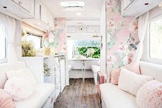 the interior of a camper with floral wallpaper and pink pillows on the couches