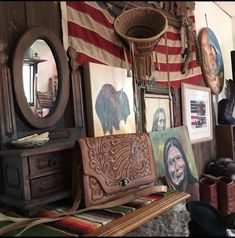 a room filled with pictures and paintings on the wall next to a wooden bench in front of an american flag