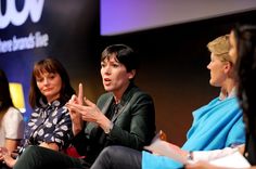 three women are sitting in chairs and one woman is making a hand gesture with her right hand