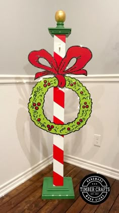 a candy cane with a wreath on it and a christmas decoration hanging from the top