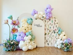 an arrangement of balloons and flowers in front of a backdrop with the words congratulations grad on it