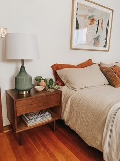 a bed sitting next to a night stand on top of a wooden floor in a bedroom