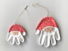 two white gloves with red and white santa claus hats hanging from the ends of them