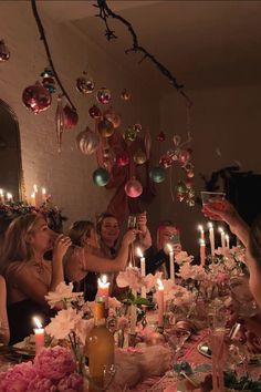 a group of people sitting around a table with candles in front of them and decorations hanging from the ceiling