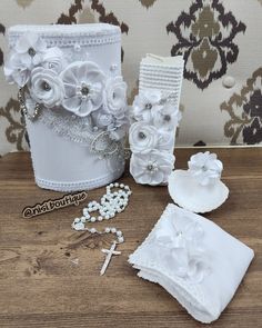 white wedding decorations on a wooden table next to a wallpapered background with flowers and pearls