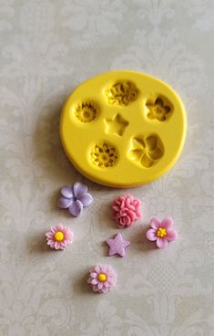 a yellow cookie mold with pink and purple flowers next to it