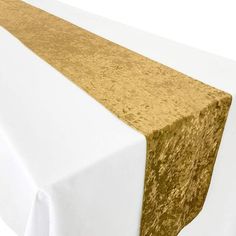 a gold and white table runner on top of a white tablecloth with a golden stripe