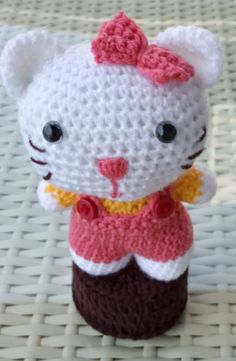 a crocheted hello kitty doll sitting on top of a cupcake with a bow