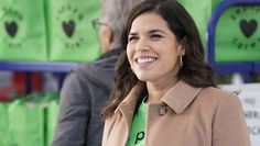 a woman standing in front of green bags with hearts on them and smiling at the camera