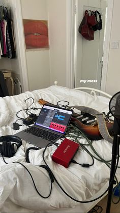 a laptop computer sitting on top of a bed next to headphones and other electronics