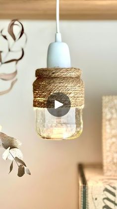 a mason jar hanging from a ceiling with twine on it and a light fixture in the background