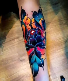 a woman's leg with colorful flowers on it and an orange flower in the center