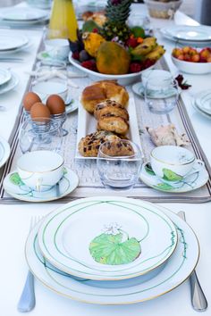 the table is set with plates, bowls, and other dishes for breakfast or brunch