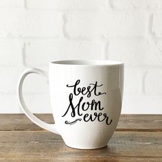 a white coffee mug with the words best mom ever on it sitting on a wooden table