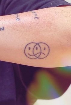 a person with a tattoo on their arm has a smiley face and two circles in the middle