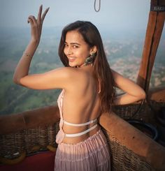 a woman standing on top of a wooden balcony next to a lush green valley in the background