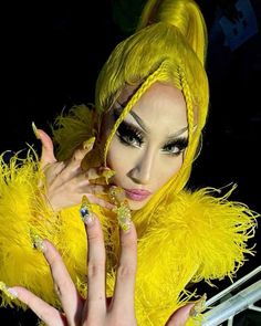 a woman with bright yellow feathers on her head and hands in front of her face