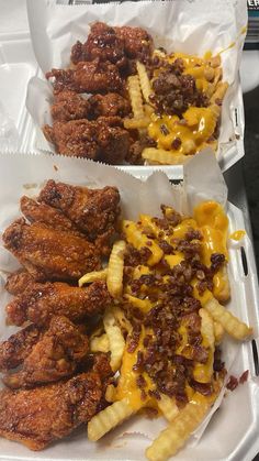 two trays filled with chicken wings and fries covered in cheese on top of them