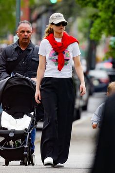 a man and woman walking down the street with a baby in a stroller next to them