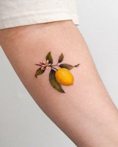 a small tattoo on the arm of a woman with an orange and flower design on it