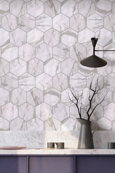 a kitchen counter with a vase on top of it next to a wall that has hexagonal tiles