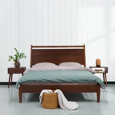 a bed sitting in a bedroom next to two nightstands and a table with a plant on it