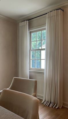 a living room with two couches and a window in the corner that has white drapes on it