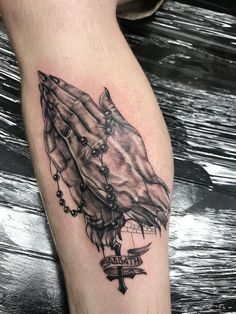 a black and white tattoo on the leg of a person with rosarys hanging from it