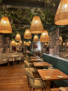 a restaurant with wooden tables and wicker lamps hanging from the ceiling over them, along with green chairs